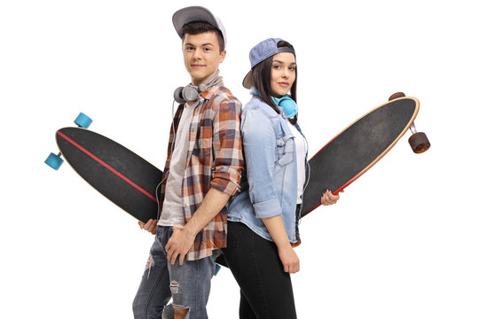 Teenage skaters with longboards with their backs against each other