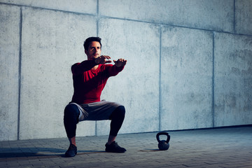 Athletic man doing squats preparing to do kettlebell exercises