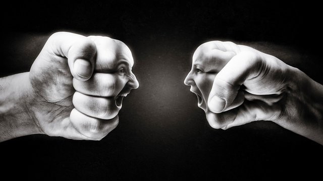 Two fists with a male and female face collide with each other on dark background. Concept of confrontation, competition, family quarrel etc. Black and white.