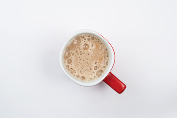top view of foamy milk coffee or milk tea in a red mug isolated on white background