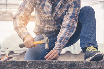 A young man using a hammer to nail concrete.