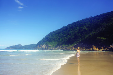 Fototapeta na wymiar young woman in skirt walking along the seashore, Brazil
