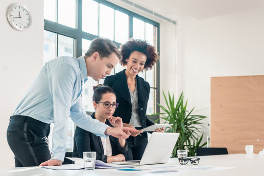 Three Members Of A Young Professional Team Working Together In A Modern Meeting Room