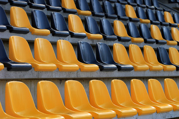 Rows of plastic black and yellow seats at a stadium