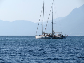Obraz premium Sailing yachts in the sea near the foggy mountain coast. Beautiful sea landscape