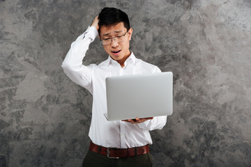 Portrait of a puzzled young asian man dressed in shirt