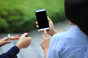 Woman using electronic gadget or checking newsfeed on social networks with her friend