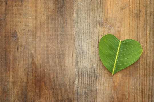 heart shaped leaf over wooden table. ecology and health concept.