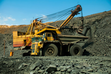 Obraz premium Excavator in the quarry loads the dumper with iron ore