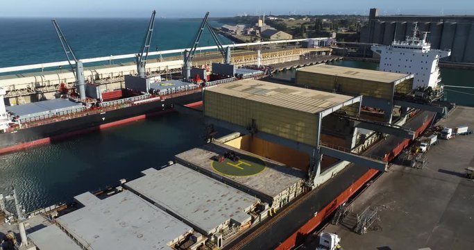 Drone pull-back of aluminum ingots being loaded onto a ship for export from Australia - 4K 30P. 