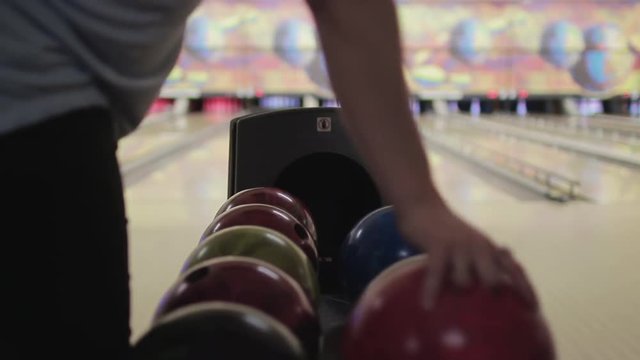 Choosing Bowling Ball. Young woman chooses a bowling ball In machine to throw