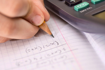 Child Holds the Pencil in his Hand and Solves Mathematical Problems. School, Education and Learning Concept.