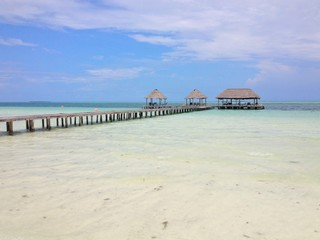 Blue sky and white clouds over a tropical pier that stretched out in to the crystal blue sea. Cayo Guilermo , Cuba