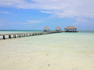 Blue sky and white clouds over a tropical pier that stretched out in to the crystal blue sea. Cayo Guilermo , Cuba