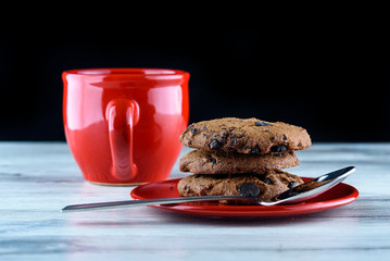 a piece of chocolate cake on a plate next to a cup of coffee, on a dark wooden background. Homemade baking.Close-up view.