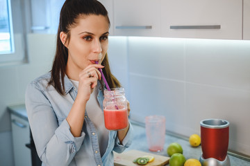 Woman drinking smoothie from the jar with a straw