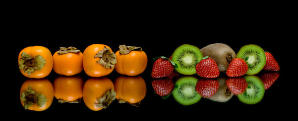 persimmon, kiwi and strawberries on a black background