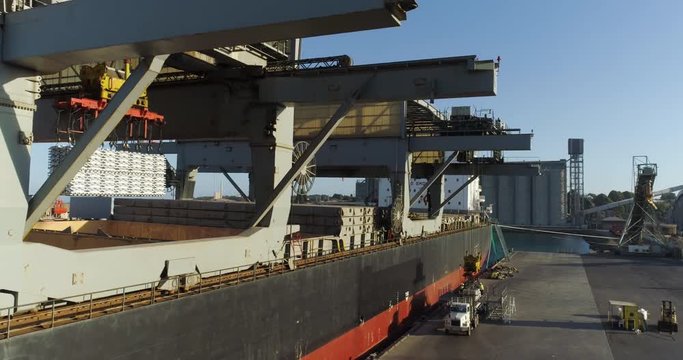 Drone tracking backwards on aluminum ingots being loaded on a ship from export from Australia - 4K 30P. 