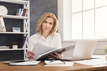 Businesswoman reading document at office desktop