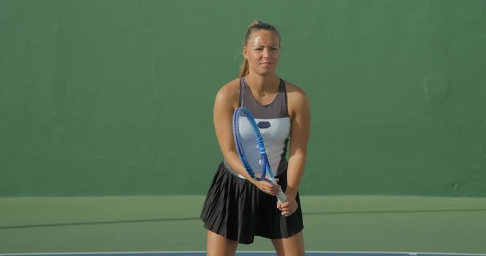 A young female tennis player hits a backhand in slow motion