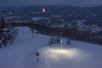 Street lamp and snow with town light and mountain background