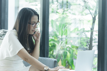 Beautiful asian attractive woman has working and talking with phone for business marketing at coffee cafe in the morning with happy and relaxing time.