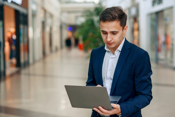 Successful young businessman working on laptop. Stylish handsome man in suit. Forex cryptocurrency trading, business concept.