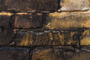 Close-up Textured background of old faded bricks stained with black oil. A brick gradient between dirty black and light yellow bricks. Grunge style