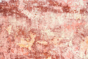 Pink-red Textured background of multi-layer flaking paint on the wall. Mixing different colors of paints in the cleaved layers on the surface. Grunge texture with a deep pattern
