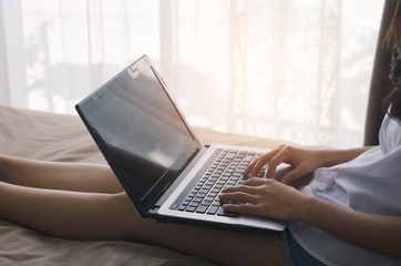 attractive woman hands using laptop working typing keyboard on the bed in sleeping room at morning after wake up. or convenient for shopping online every time and every where concept.
