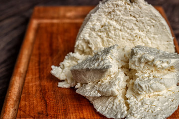 Cheese, cottage cheese on a wooden background, fresh cottage cheese in gauze, dairy product, healthy food. View from above. Goat, cow-baked cottage cheese in a rustic style.