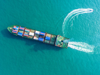 Container ship in export and import business and logistics. Shipping cargo to harbor by crane. Water transport International. Aerial view