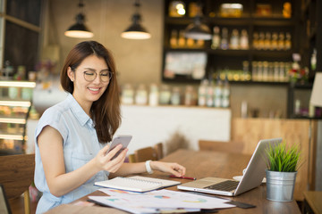 woman using smart phone and laptop in cafe.