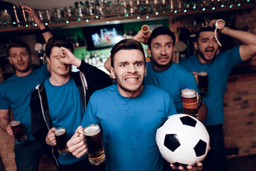 Five soccer fans drinking beer sad that their team looses at sports bar.