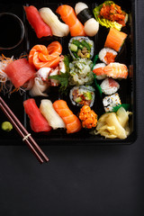 Japanese set of sushi, sashimi and roll with vegetables on a black background side view from above.
