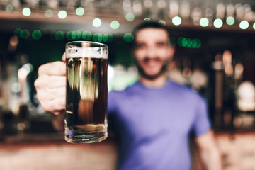 Close up barmen holding glass of beer at sports bar.