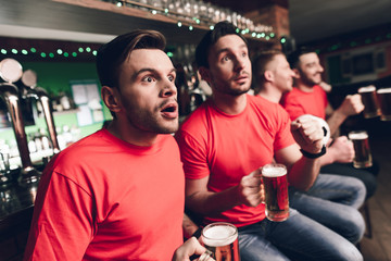 Soccer fans freeze in anticipation waiting for goal at sports bar.