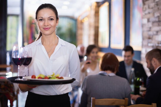 Professional waitress holding serving tray for restaurant guests