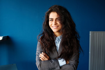 Image of happy young business woman in office looking aside.