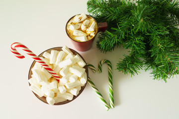 Christmas background, greeting card with a Cup of coffee or chocolate with marshmallows,candy canes, a red plate and tree branches