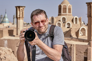 Tourist with a camera photographing an ancient city, Kashan, Iran.