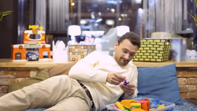 Adult man plays with kid constructor in children's room in cafe