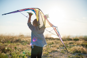 dreamy little boy running with big kite in his hands over his head