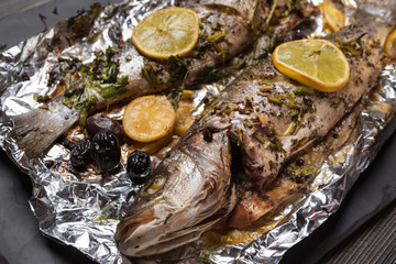 two seabass fish baked in the oven or on the grill, on food foil