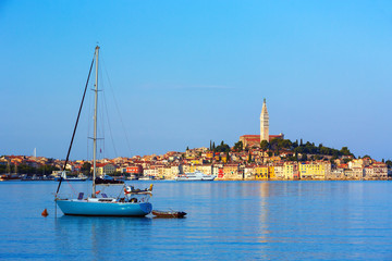 Fototapeta na wymiar Sail boat enters the harbor of old Venetian town of Rovinj, Croatia