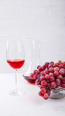 Wine Pink and Grape bunch. Alcoholic drink in a glass glass on a light background.Copy space for Text. selective focus.