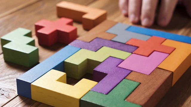 IQ test. Concept of decision making process, logical thinking. Logical tasks. Conundrum, find the missing piece of the proposed. The man's hand chooses the right geometric shape and puts it in place.