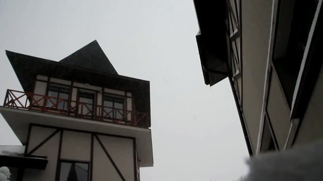 The winter sky and snow falling on the background of the roof of a vintage house. Snow and vintage. Back background for the inscriptions and text on the background of the roof of the house and the bli