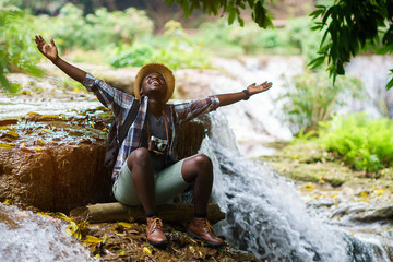 African Man Traveler with backpack sitting and relaxing freedom with waterfall