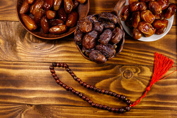 Dates fruit and rosary on wooden table. Top view